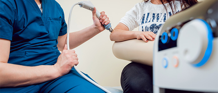 A woman getting shockwave therapy on her elbow.